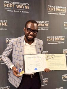 Charles Dankyi displaying his Beta Gamma Sigma certificate and 2026 MBA Student Leadership Award